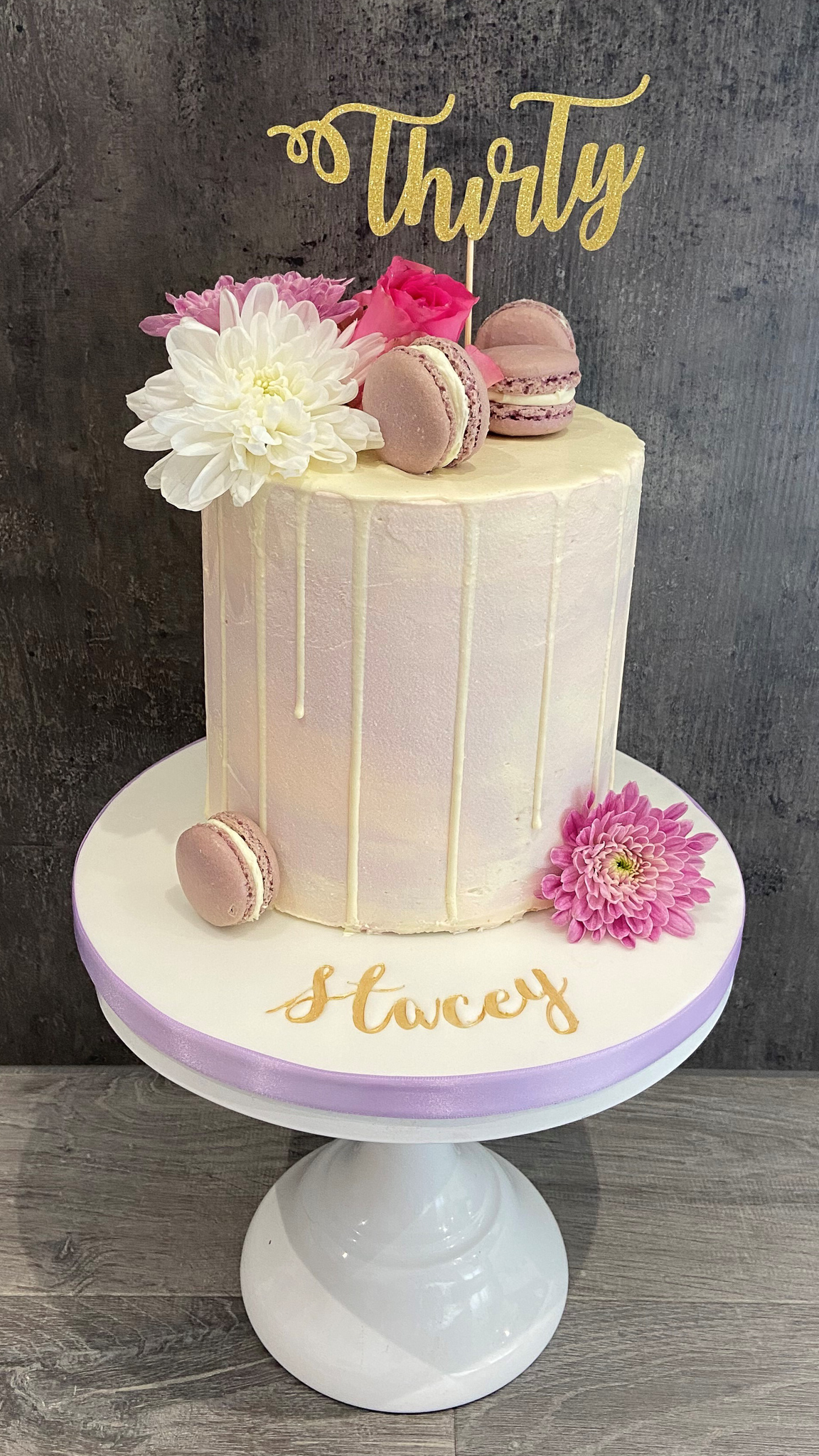 Pastel coloured buttercream drip cake with macarons and fresh flowers
