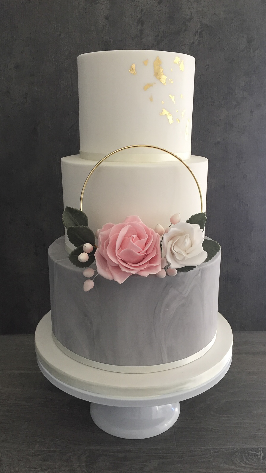 Three-tier wedding cake with floral hoop and edible gold leaf