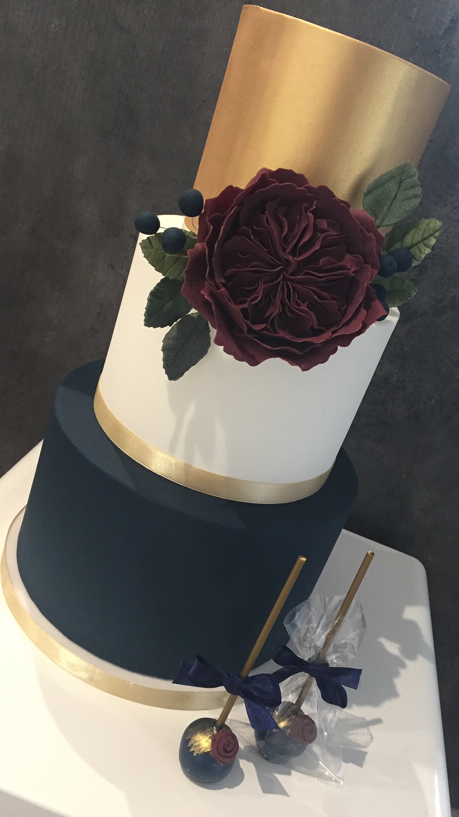 Navy white and gold wedding cake with burgundy David Austin rose and matching cake pops