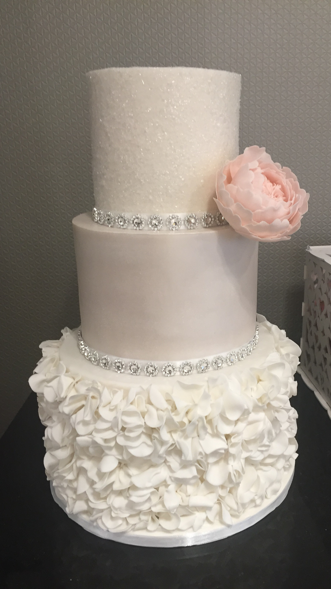 Three tier pretty wedding cake with sugar ruffles sparkles and sugar peony